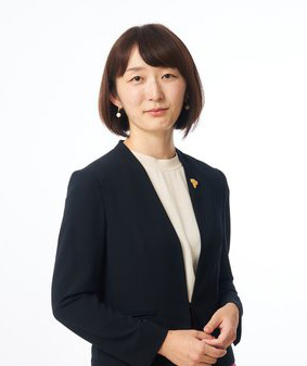 マイ先生のポートレート写真。紺のジャケットに葡萄のブローチ。